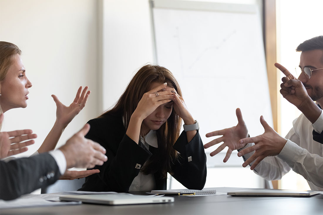 woman at office sitting in the middle of two angry people