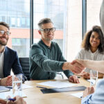 businessman and businesswoman shaking hands and negotiation at group meeting