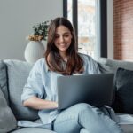 woman sitting on her couch using her computer