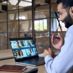 Manager sits at desk on a Zoom call and leads colleagues in a remote environment