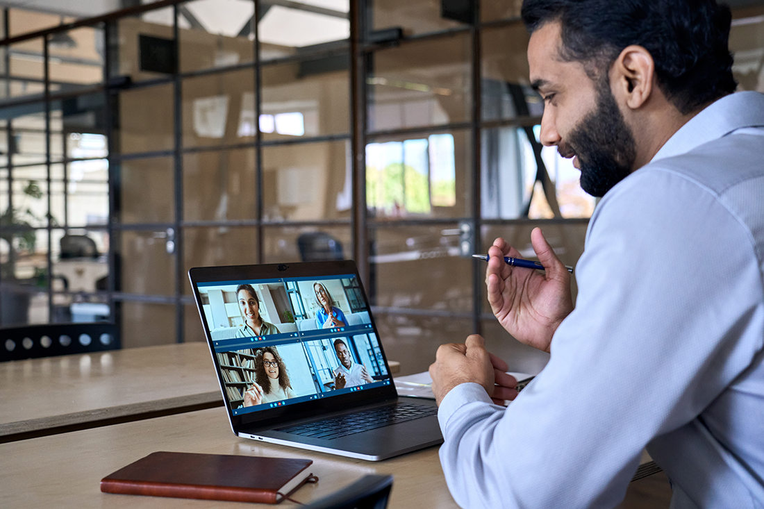 Manager sits at desk on a Zoom call and leads colleagues in a remote environment