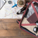 A top view of accessories and travel items with a map on a wooden board