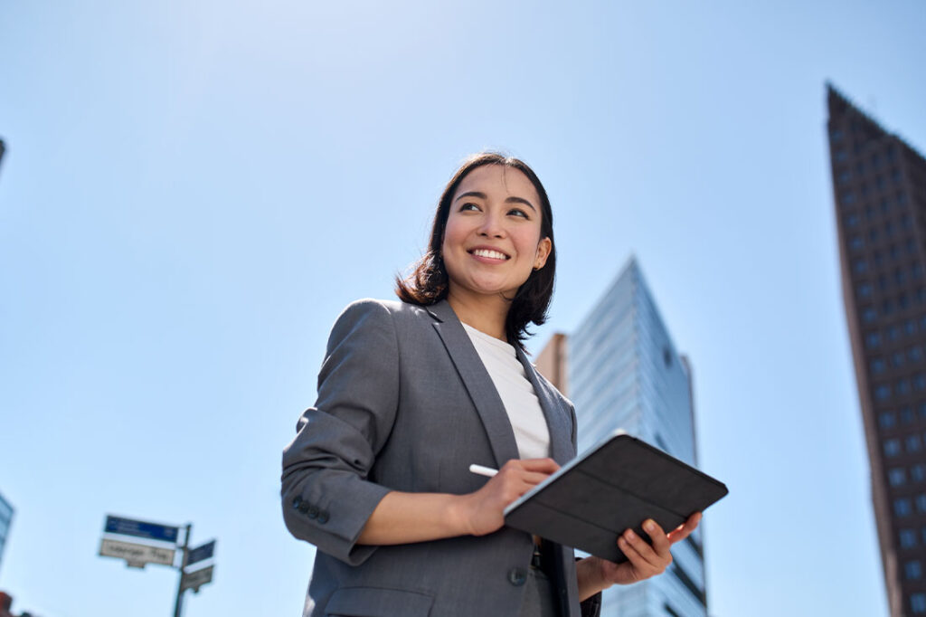 business woman holding tablet standing on the street in big city