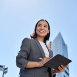 business woman holding tablet standing on the street in big city