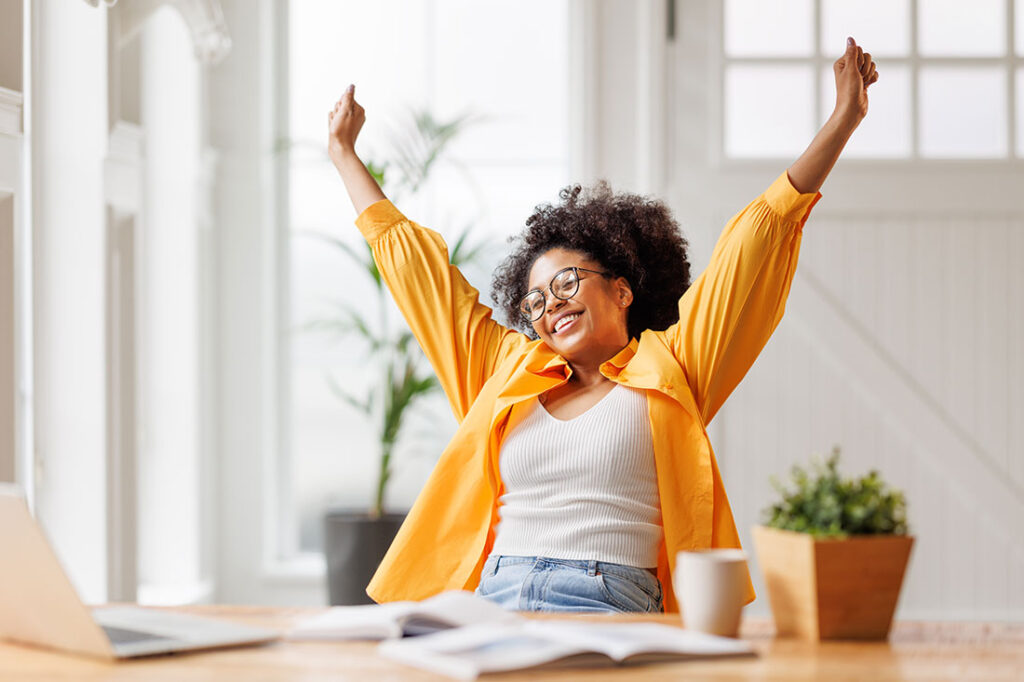 business woman smiling and rejoices while sitting at desk