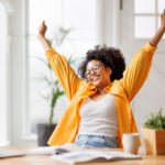 business woman smiling and rejoices while sitting at desk