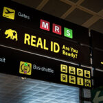 Illuminated airport signage displaying the Real ID compliance, reminding passengers at airport of new travel document requirements.