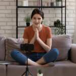 blogger influencer sit on couch at home shoot live broadcast on smartphone