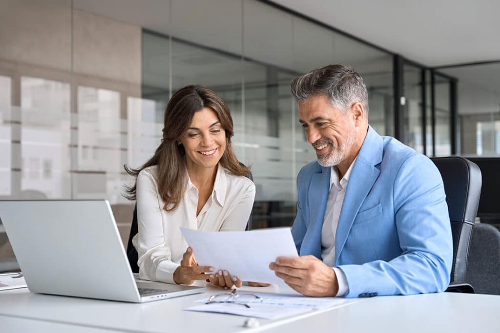 Two middle aged professionals man and woman checking document reading report