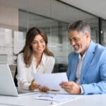 Two middle aged professionals man and woman checking document reading report