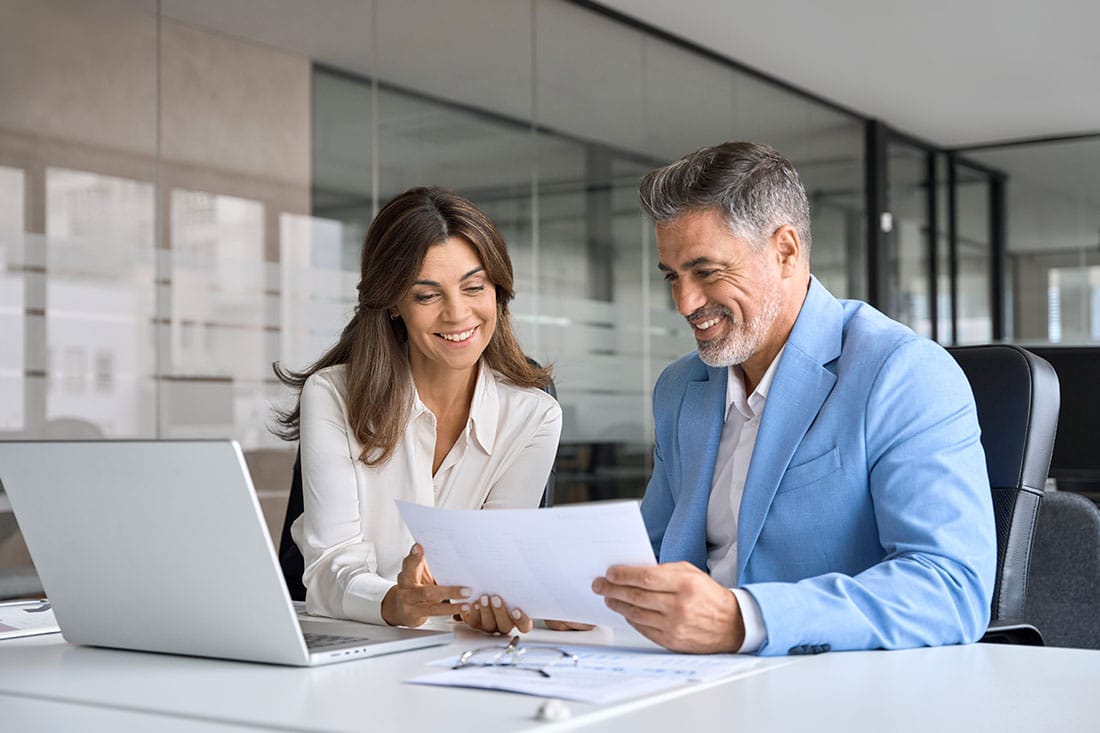 Two middle aged professionals man and woman checking document reading report