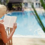 A woman reading in front of a pool.
