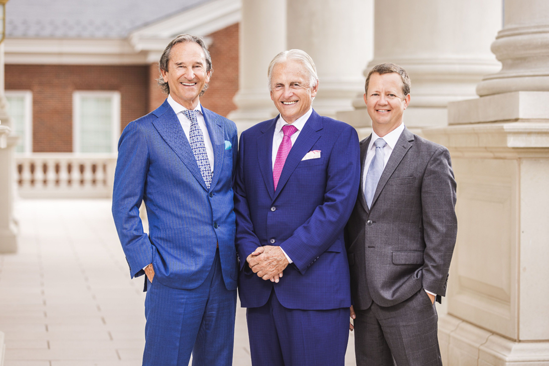 Three men in suits standing together.