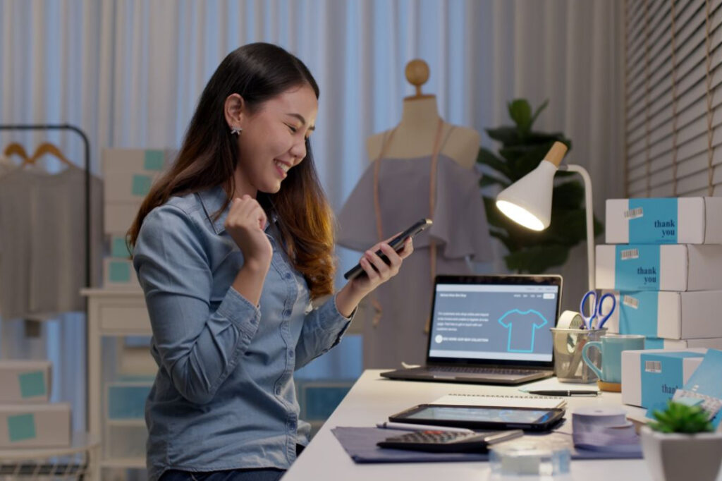 a woman business owner sitting at her desk in her office while smiling at her phone