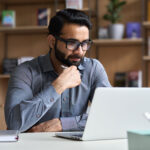 Young professional business man, focused wearing glasses working on laptop