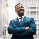 male entrepreneur in business suit looking up with city backdrop
