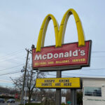 The iconic golden arches of McDonalds with a sign featuring their new Krispy Kreme Donuts menu items