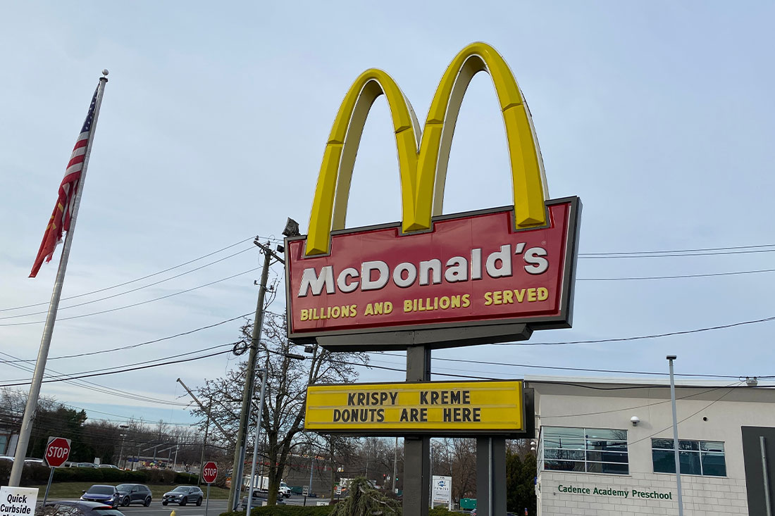 The iconic golden arches of McDonalds with a sign featuring their new Krispy Kreme Donuts menu items