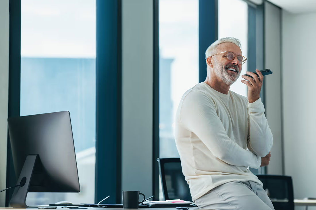 man sitting on office desk talking on his cell phone