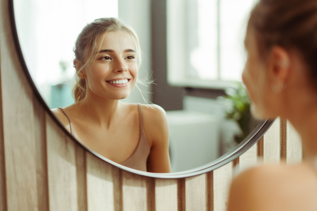 Woman smiling in the mirror practicing positive self talk