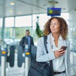 Woman smiling holding her phone in airport