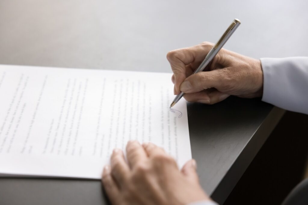 Close up on a hand signing a letter.