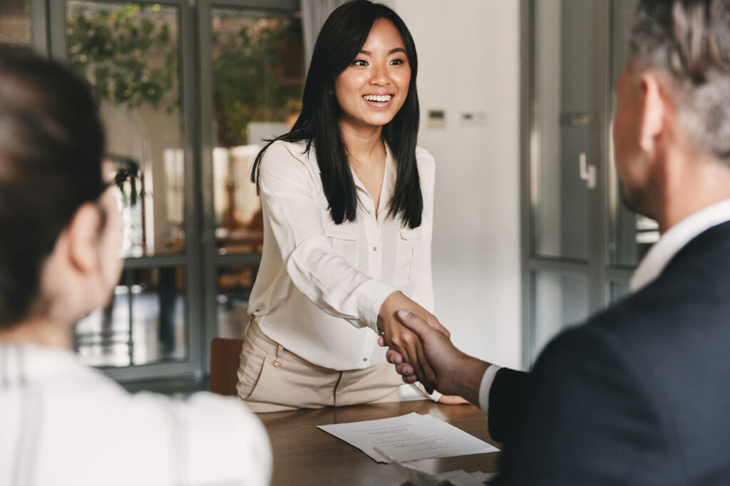 shaking hand of young asian woman after successful interview