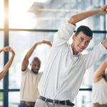 Office workers stretching together as part of their wellness benefits