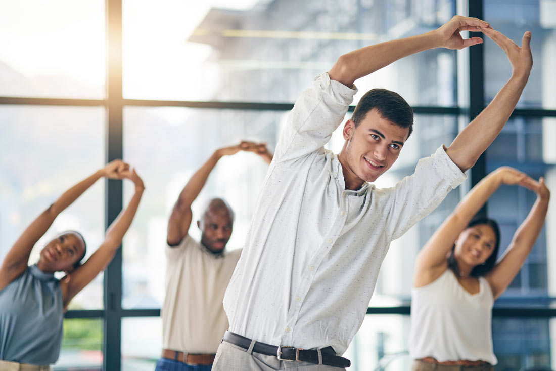Office workers stretching together as part of their wellness benefits