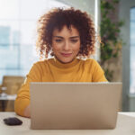 Woman with curly hair using laptop in modern office