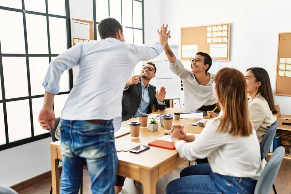 Motivated employees high fiving at work