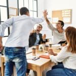 Motivated employees high fiving at work