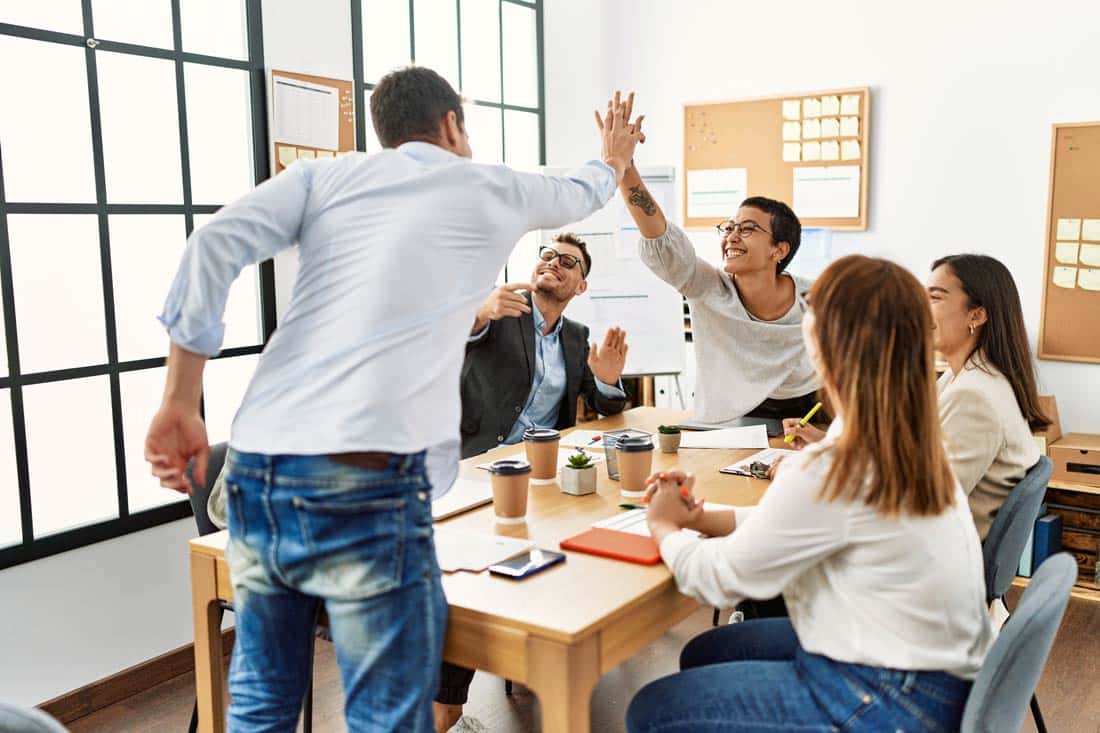 Motivated employees high fiving at work