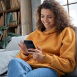 woman sitting on a couch scrolling through her phone