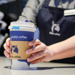 barista holding a cup of Luckin Coffee to customer