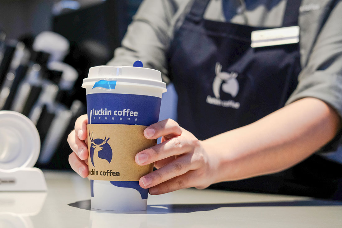 barista holding a cup of Luckin Coffee to customer