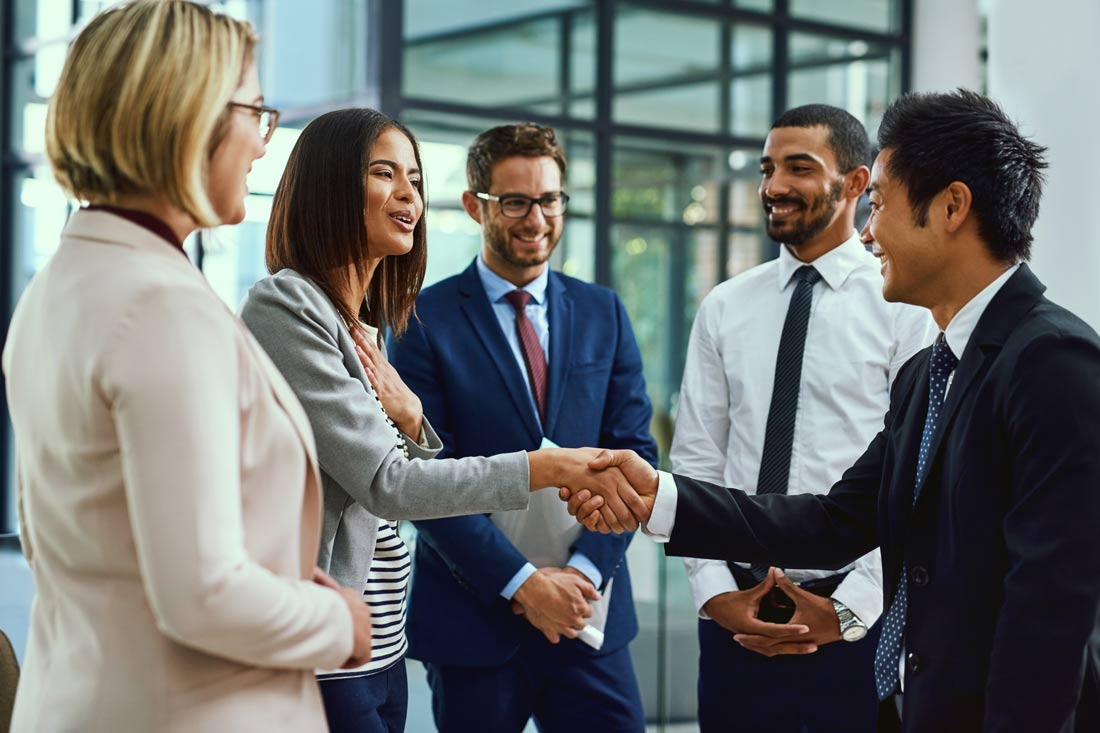 Five professionals shaking hands during a leadership transition to maintain company morale