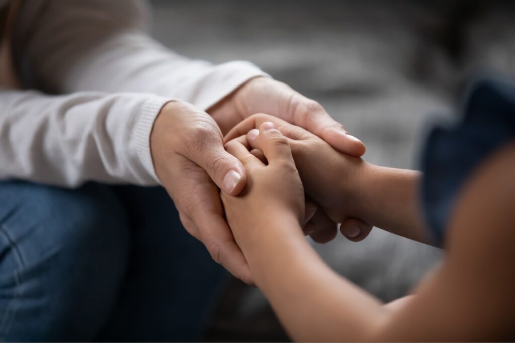 Close on an adult's hands embracing a child's hands.
