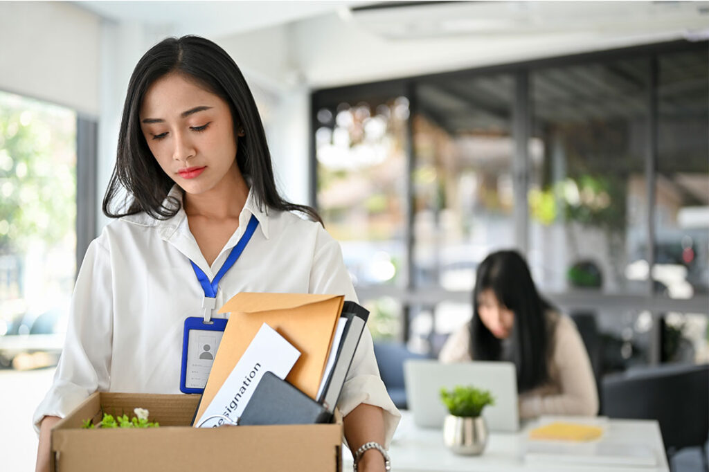 female office worker holding a cardboard box with her belongings