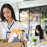 female office worker holding a cardboard box with her belongings
