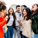 Young group of happy multiracial friends laughing together outdoor