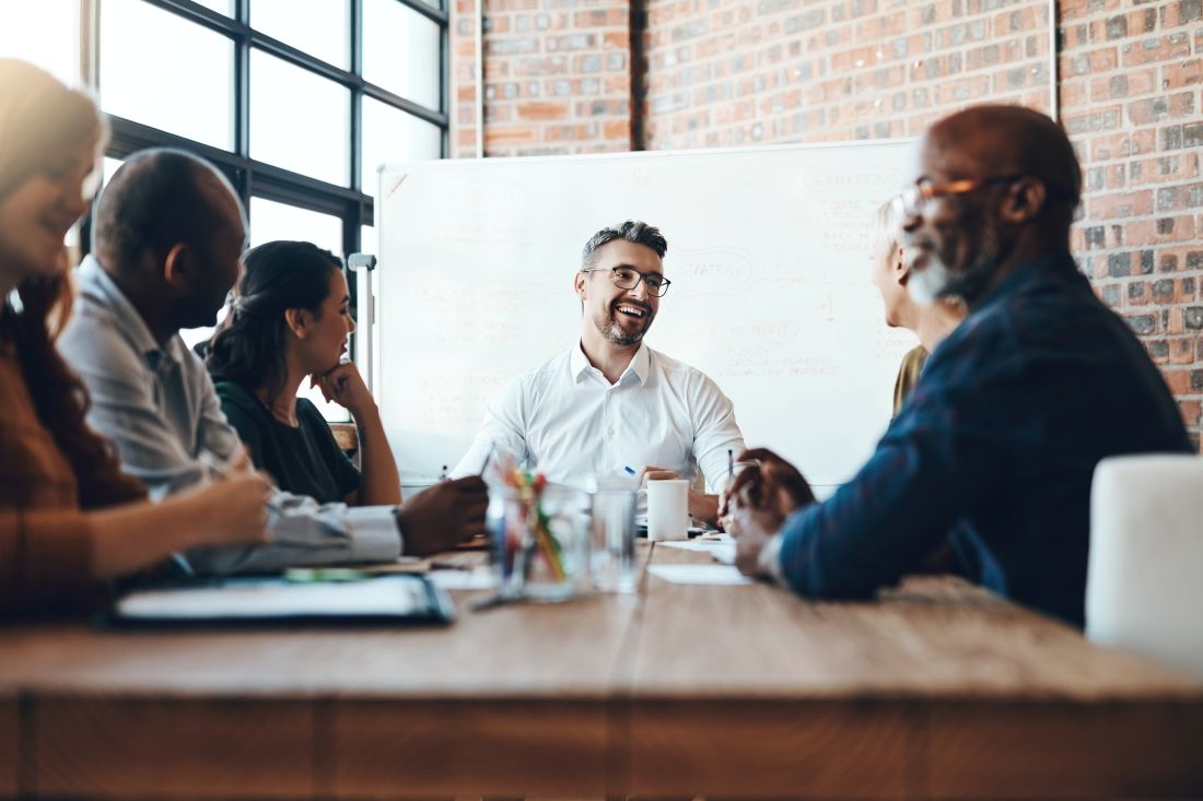 a boss sitting in an office and having a team meeting with employees