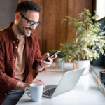 man in stylish casual clothes using smartphone and laptop computer