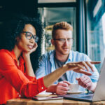 female pointing with finger on laptop computer during collaboration with male colleague