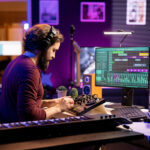 Young artist mixing and mastering tunes on professional console