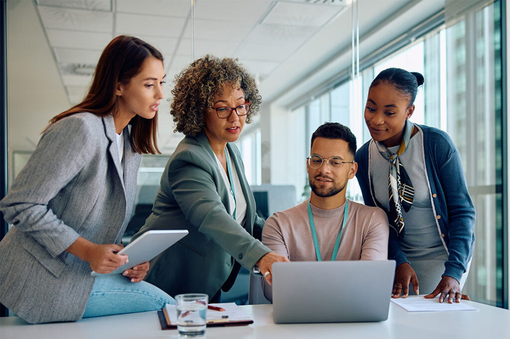 Group of coworkers working on a computer during business meeting in the office