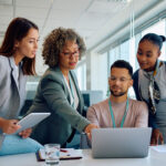 Group of coworkers working on a computer during business meeting in the office