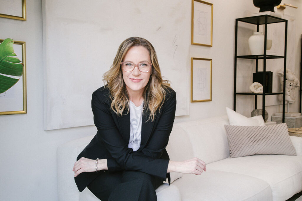 Allison Graham in suit on couch with arms crossed